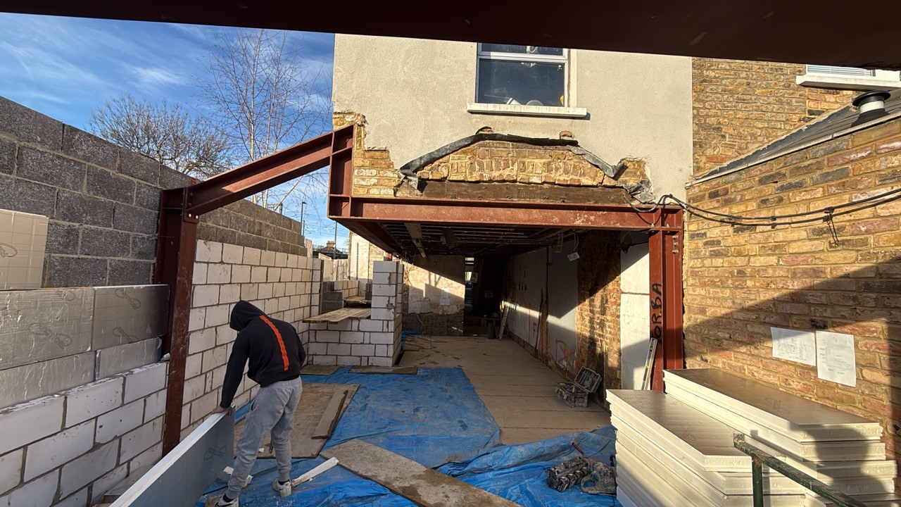 Exposed steel beams and blockwork during building work at the rear of a house
