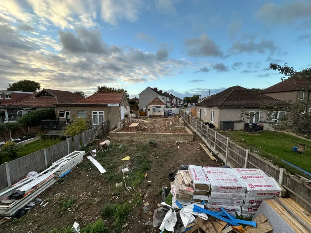 View along the Hornchurch building site with low masonry walls and stored materials